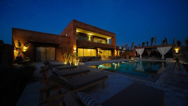 A modern two-story house with a swimming pool, outdoor seating, and ambient lighting. - To complete (Marrakech)