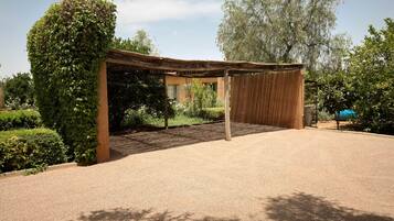 Un espace extérieur abrité, doté d’un sol en gravier et entouré de verdure et d’arbres.