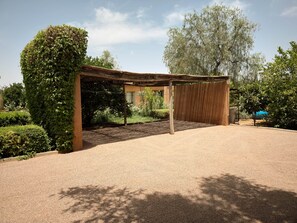 Un espace extérieur abrité, doté d’un sol en gravier et entouré de verdure et d’arbres.