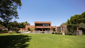A modern two-story house with a swimming pool, surrounded by a well-maintained lawn and various plants. - To complete (Marrakech)