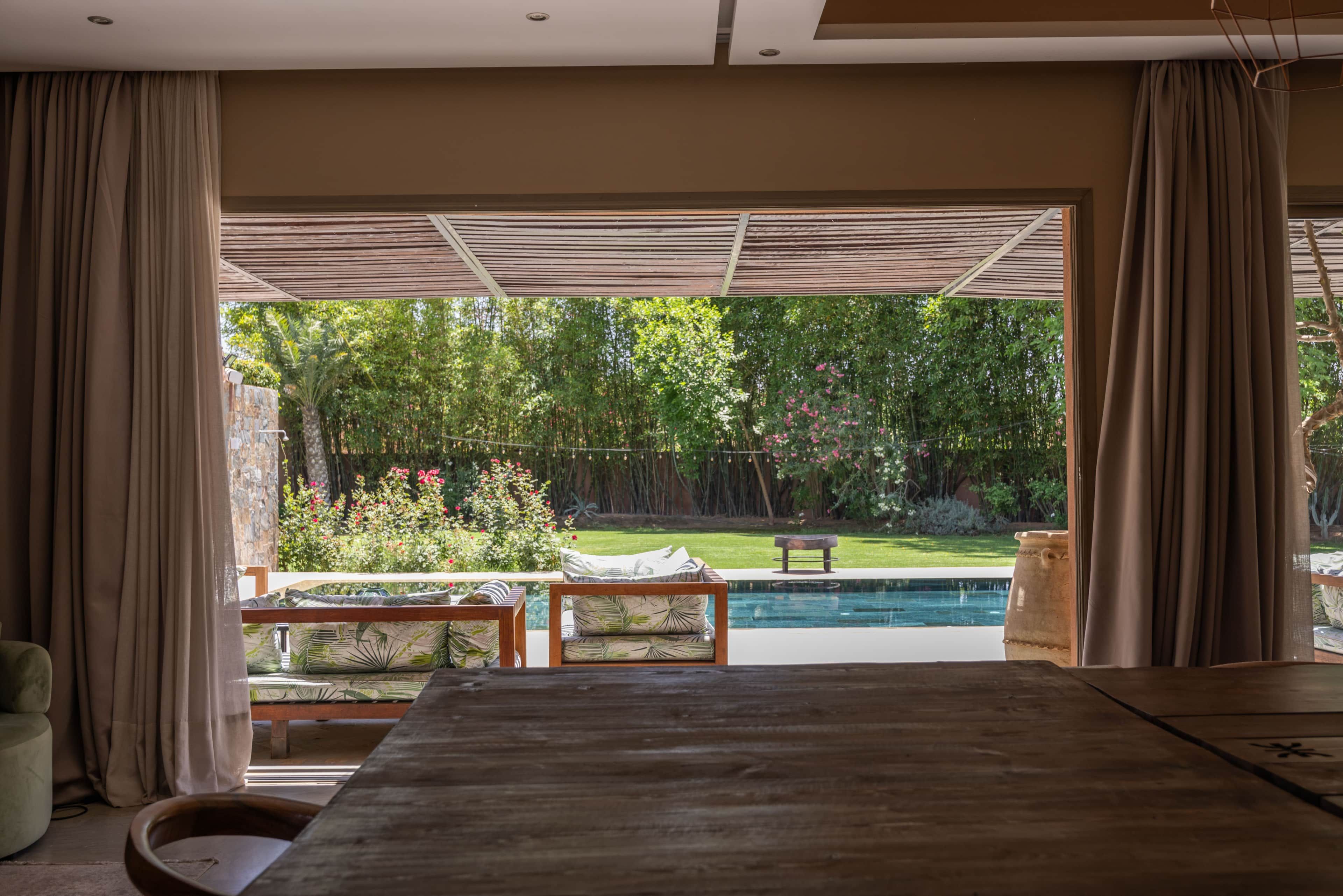 Ein Zimmer mit großem Fenster und Blick auf Pool und Garten.