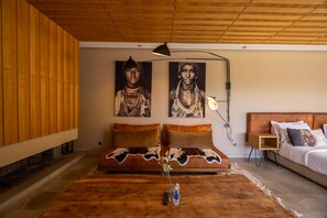 Een moderne woonkamer met een houten plafond, een bank met een koeienhuid bekleding, een salontafel met een vaas, en een bed met een houten hoofdbord.