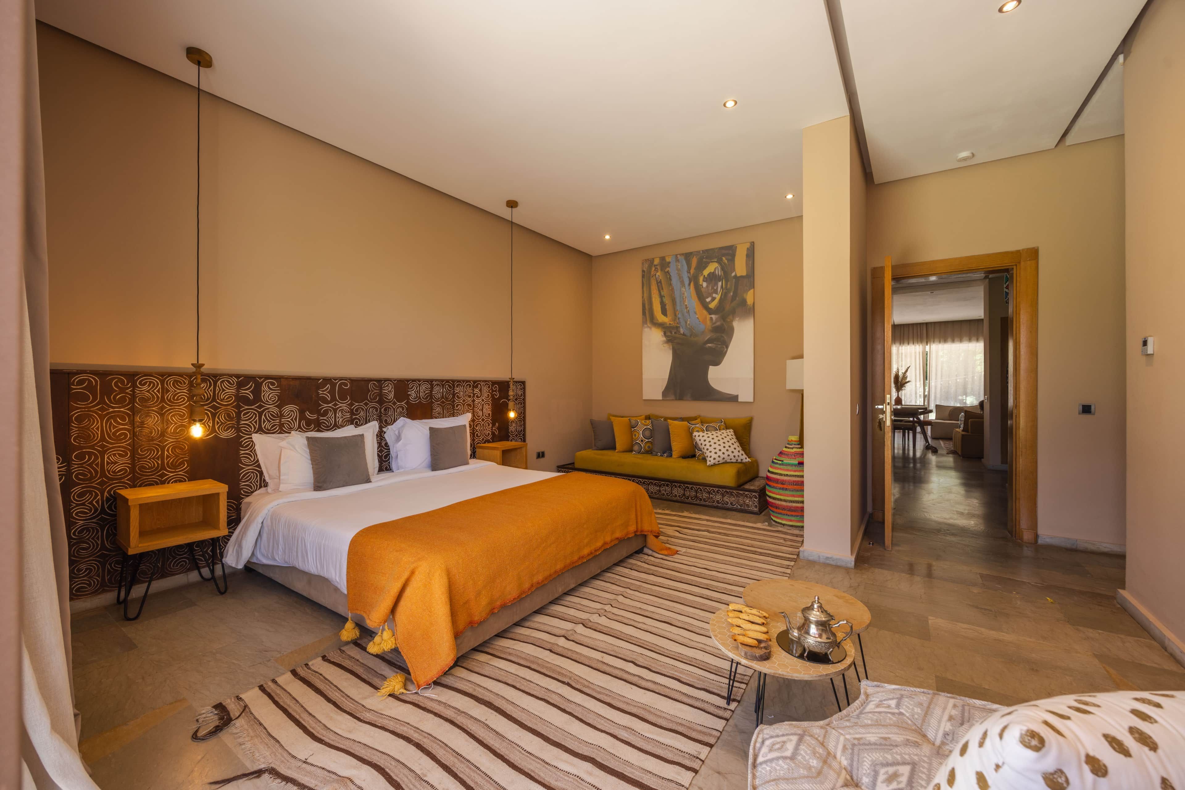 A hotel room with a large bed, a sofa, a coffee table, and a painting on the wall.