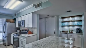A modern kitchen with granite countertops, stainless steel appliances, and white cabinetry. - Steps from YOUR Balcony to Beach | Excellent Reviews | Beach Service Included (Miramar Beach)