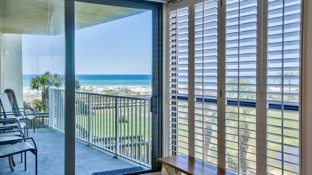 A balcony with a view of the ocean, a seating area with chairs, and a table. - Steps from YOUR Balcony to Beach | Excellent Reviews | Beach Service Included (Miramar Beach)