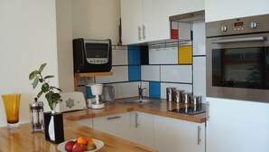 Eine moderne Küche mit weißen Schränken, einer Holz Arbeitsplatte, einer Kaffeemaschine, einem Toaster, einem Spülbecken und einem Backofen.
