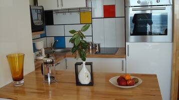 Een keuken met een koffiezetapparaat, een plant en een fruitschaal op het aanrecht.