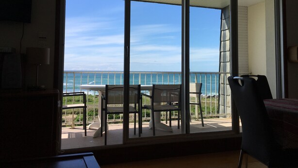 Ein Zimmer mit einer großen Schiebeglasdoor zum Balkon mit Meerblick.