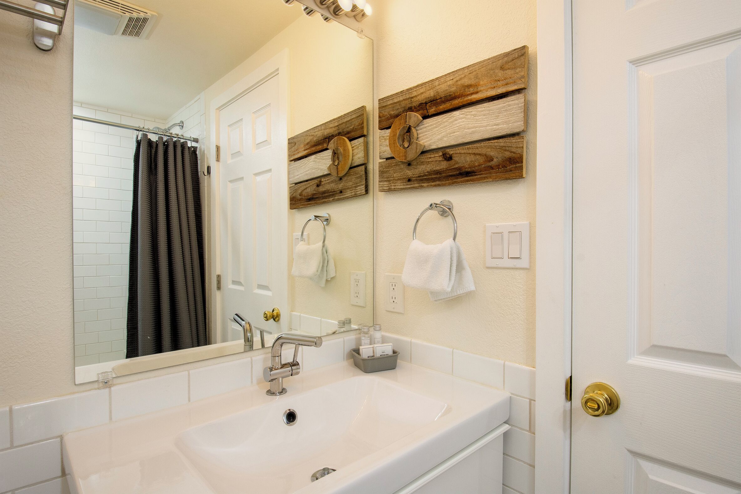 A bathroom with a white sink, a mirror, and wooden wall decor.