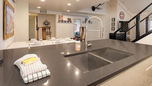 Cocina moderna con una isla grande, pileta de acero inoxidable y un trofeo de venado montado.