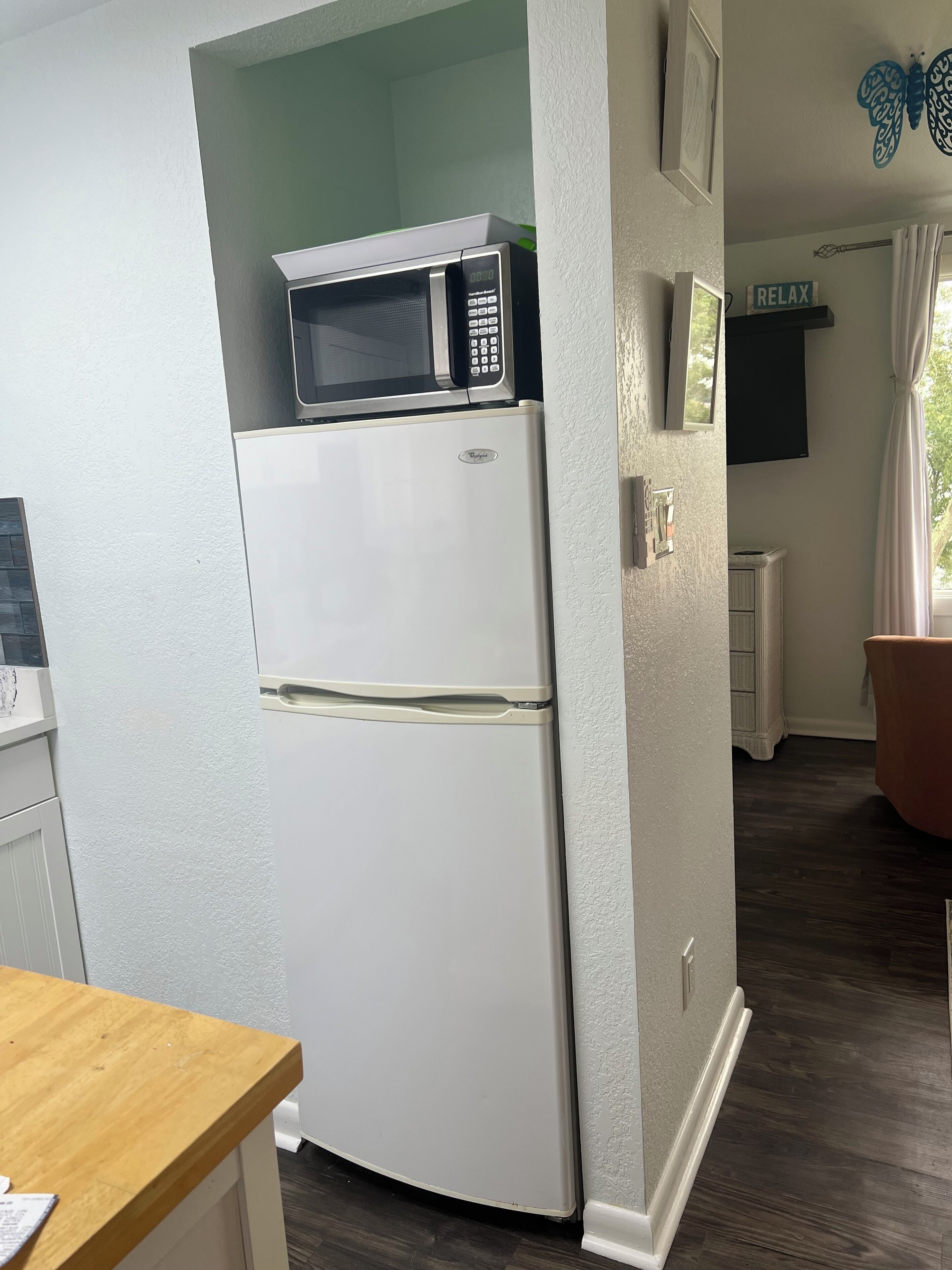 A kitchen with a white refrigerator, a microwave on top, and a wooden table.