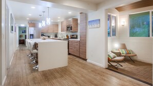 A modern kitchen with a central island, wooden cabinets, and pendant lighting. - The Perfect large Family Beach Getaway! 3 Min Walk To Beach - Family reunions! (Encinitas)