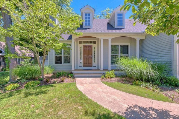 A two-story house with a front porch, a wooden door, and a small front yard with a pathway leading to the door. - Douglas Beach Rental - Close to everything! Sleeps up to 12. (Douglas)