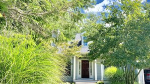 A house with a front porch, surrounded by lush greenery and trees. - Douglas Beach Rental - Close to everything! Sleeps up to 12.  (Douglas)