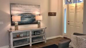 A hallway with a white console table, two lamps, a painting, and a sign that reads "LAKE". - Douglas Beach Rental - Close to everything! Sleeps up to 12.  (Douglas)