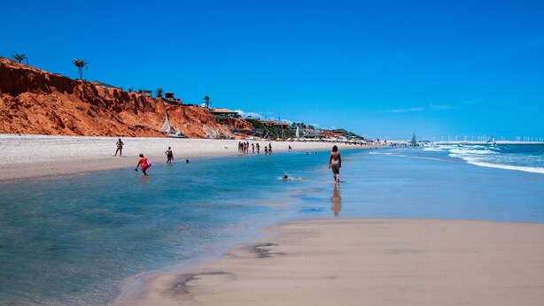 A beach with clear blue water, sandy shore, and a few people. - Hotel Alta Vista (Aracati)