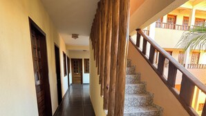 A hallway with a wooden staircase leading to an upper floor. The walls are painted in a light color, and the floor is tiled. - Hotel Alta Vista (Aracati)