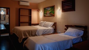 A room with two beds, a wooden headboard, a painting on the wall, and a shelf unit. - Hotel Alta Vista (Aracati)
