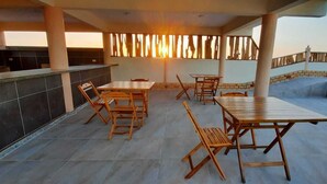 An outdoor patio with a dining area, including tables and chairs, and a kitchen area with a counter and cabinets. - Hotel Alta Vista (Aracati)