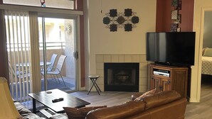 Un salon avec une cheminée, un téléviseur, un canapé et un ventilateur de plafond.