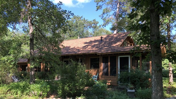 A rustic cabin with a stone foundation, a wooden deck, and a large window. - Quiet and peaceful cottage in Crosslake (Crosslake)