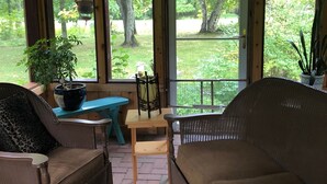 A cozy room with a wooden ceiling, large windows, a sofa, a chair, a small table, and a potted plant. - Quiet and peaceful cottage in Crosslake (Crosslake)