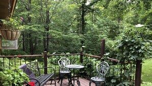 A wooden deck with metal chairs and tables, surrounded by lush greenery and trees. - Quiet and peaceful cottage in Crosslake (Crosslake)