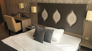 Une chambre d’hôtel équipée d’un lit, d’un bureau, d’une chaise et de deux lampes fixées au mur.