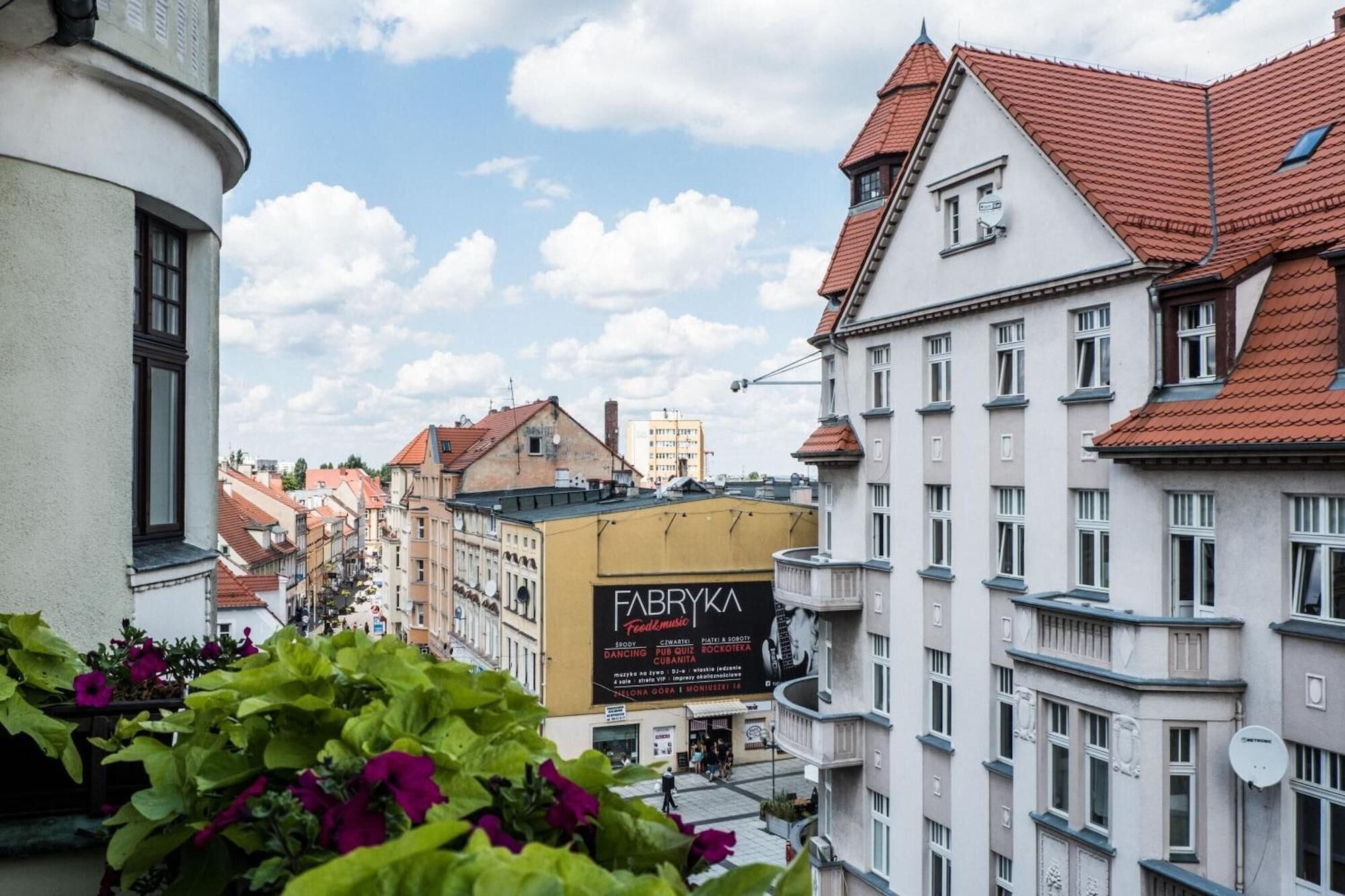 Vista de una calle con edificios, uno de ellos con un cartel que dice 'FABRYKA Feedmusic'.