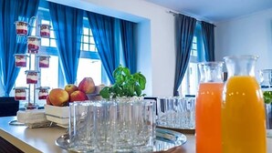 Un plateau contenant un assortiment de fruits, des verres et des bouteilles de jus, préparé pour le petit-déjeuner.