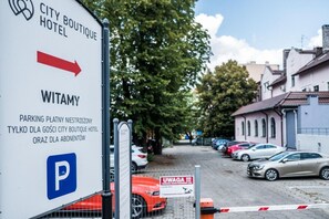 A sign for City Boutique Hotel with directions to parking and a nearby church.