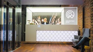 Un espace d’accueil au design moderne, comprenant un comptoir d’accueil, un coin salon et un ascenseur en verre.
