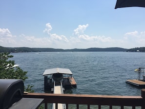 A lakeside view with a dock extending into the water, surrounded by greenery and a clear sky. - Cozy lake in front of the home (Gravois Mills)