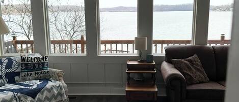 A living room with a view of a lake, a sofa, a coffee table, and a lamp.