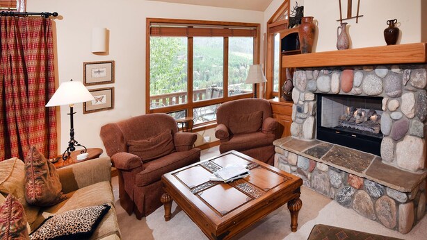 Una sala de estar acogedora con chimenea, dos sillones, una mesita de centro y vistas al exterior.