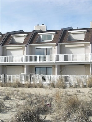 Stunning multi-story building with a central entrance and balconies, set amidst a beautiful beach and lush surroundings.