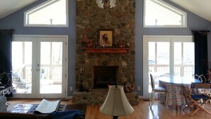 A spacious living room with a stone fireplace, high ceilings, and large windows. - 4/3, Waterfront Home w/ Covered Dock, Child Sand Play Pit,  Pet Friendly! (Seneca)