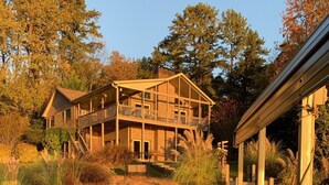 A wooden dock leading to a house with a balcony, surrounded by trees and a calm body of water. - 4/3, Waterfront Home w/ Covered Dock, Child Sand Play Pit,  Pet Friendly! (Seneca)