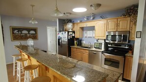 A kitchen with granite countertops, wooden stools, stainless steel appliances, and a large island. - 4/3, Waterfront Home w/ Covered Dock, Child Sand Play Pit,  Pet Friendly! (Seneca)
