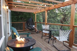 Une terrasse en bois avec un foyer, des sièges d’extérieur et des guirlandes lumineuses.