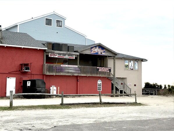 A building with a red facade, a blue roof, and a sign for 'Surf Shop Rentals'.