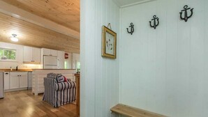 A room with a wooden ceiling, white walls, a framed picture, and three black anchors on the wall.