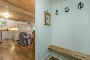 Ein Zimmer mit Holzboden, weißen Wänden, einem gerahmten Bild und drei schwarzen Ankern an der Wand.