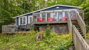 A cabin with a deck, red chairs, and a staircase.