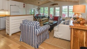 A cozy living area with striped sofas, a dining table, and a kitchen with white cabinets.