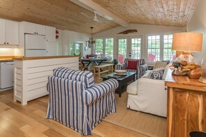 Ein gemütlicher Wohnbereich mit gestreiften Sofas, einem Esstisch und einer Küche mit weißen Schränken.