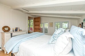 Une chambre à coucher comprenant un lit, une commode et une porte donnant sur une autre pièce.