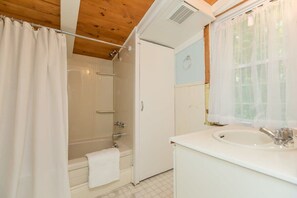 Une salle de bain avec une baignoire, un lavabo et un rideau de douche.