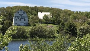 The Anne of Green Gables Museum surrounded by lush greenery and a body of water. - Rest Ashored in Anne's land!- Hot tub, Kayaks Centrally located, stunning views. (Kensington)