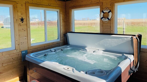 A wooden cabin with a hot tub, large windows, and a welcome sign. - Rest Ashored in Anne's land!- Hot tub, Kayaks Centrally located, stunning views. (Kensington)